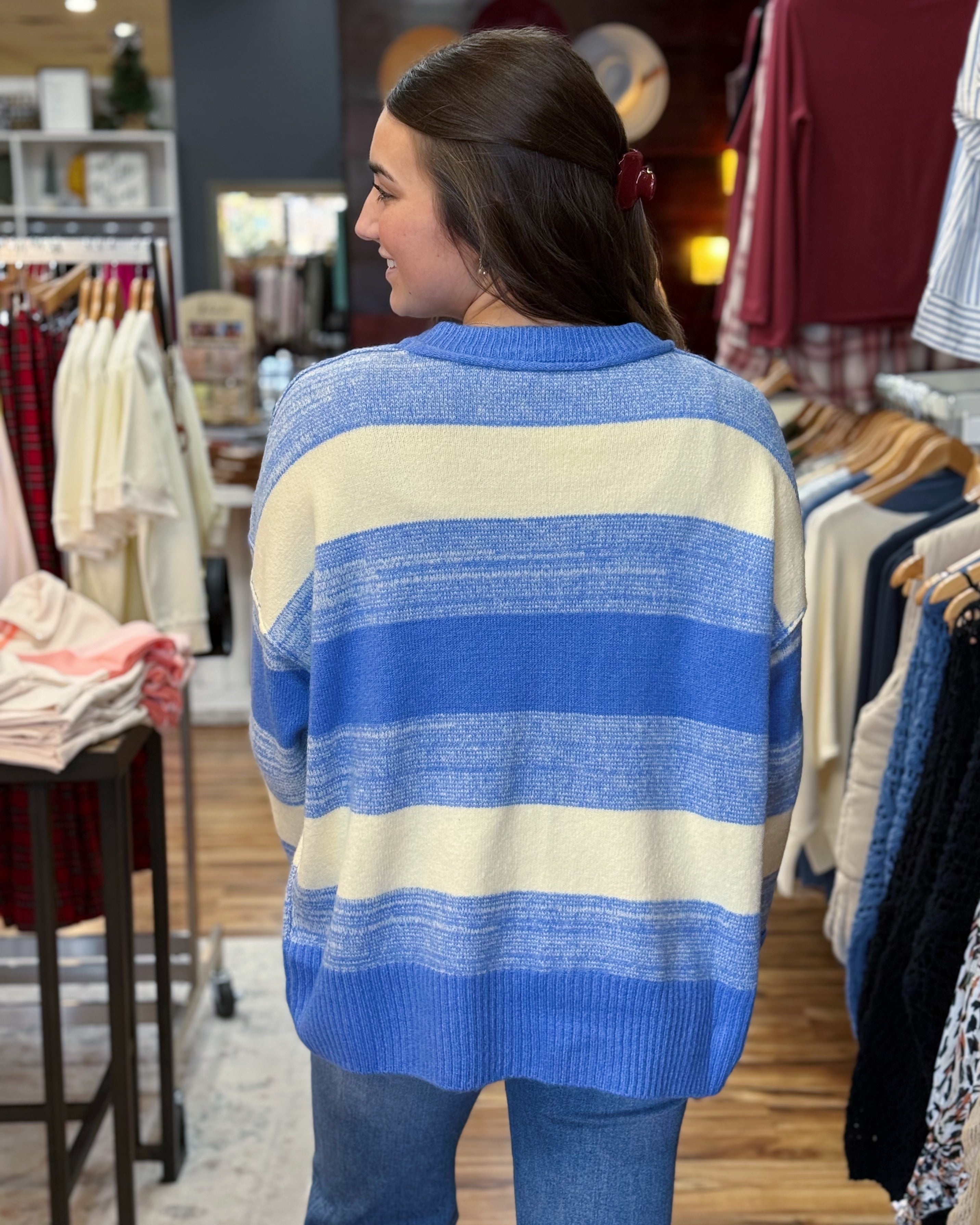 Woman wearing a blue and white striped sweater in a clothing store.