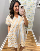 Woman taking a mirror selfie wearing a natural and white striped dress.