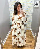 woman wearing a cream maxi dress with brown, black and taupe floral pattern. 