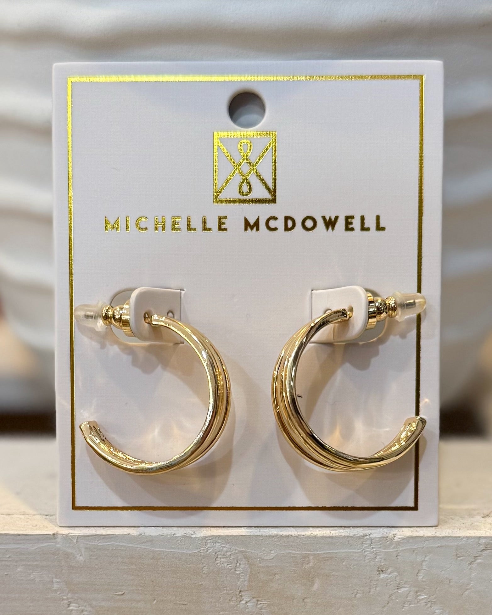 Gold hoop earrings on a Michelle McDowell branded card.