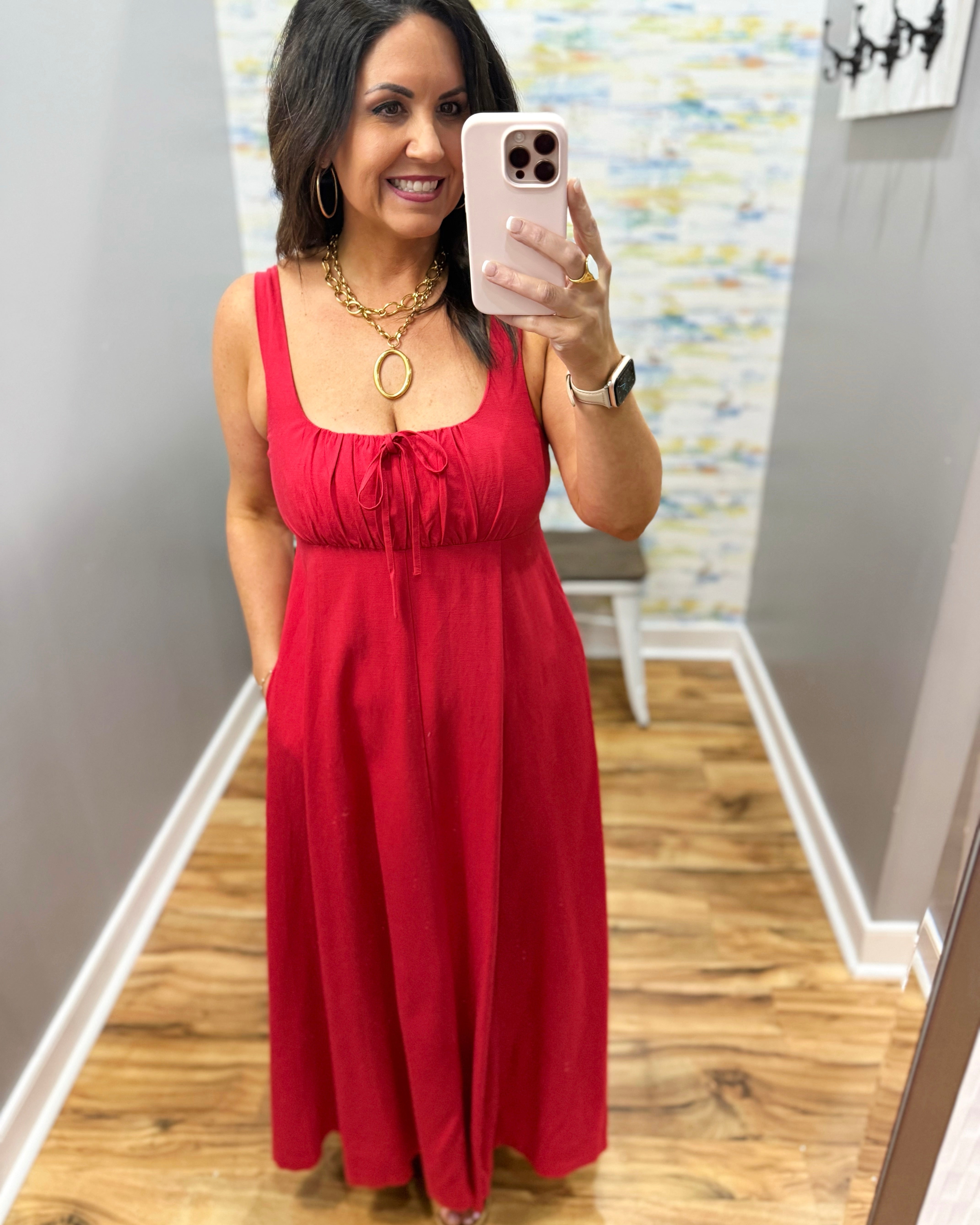 Woman wearing a red dress in a room with wooden flooring and a colorful wall.
