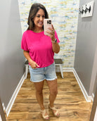 woman wearing hot pink tee with denim shorts.
