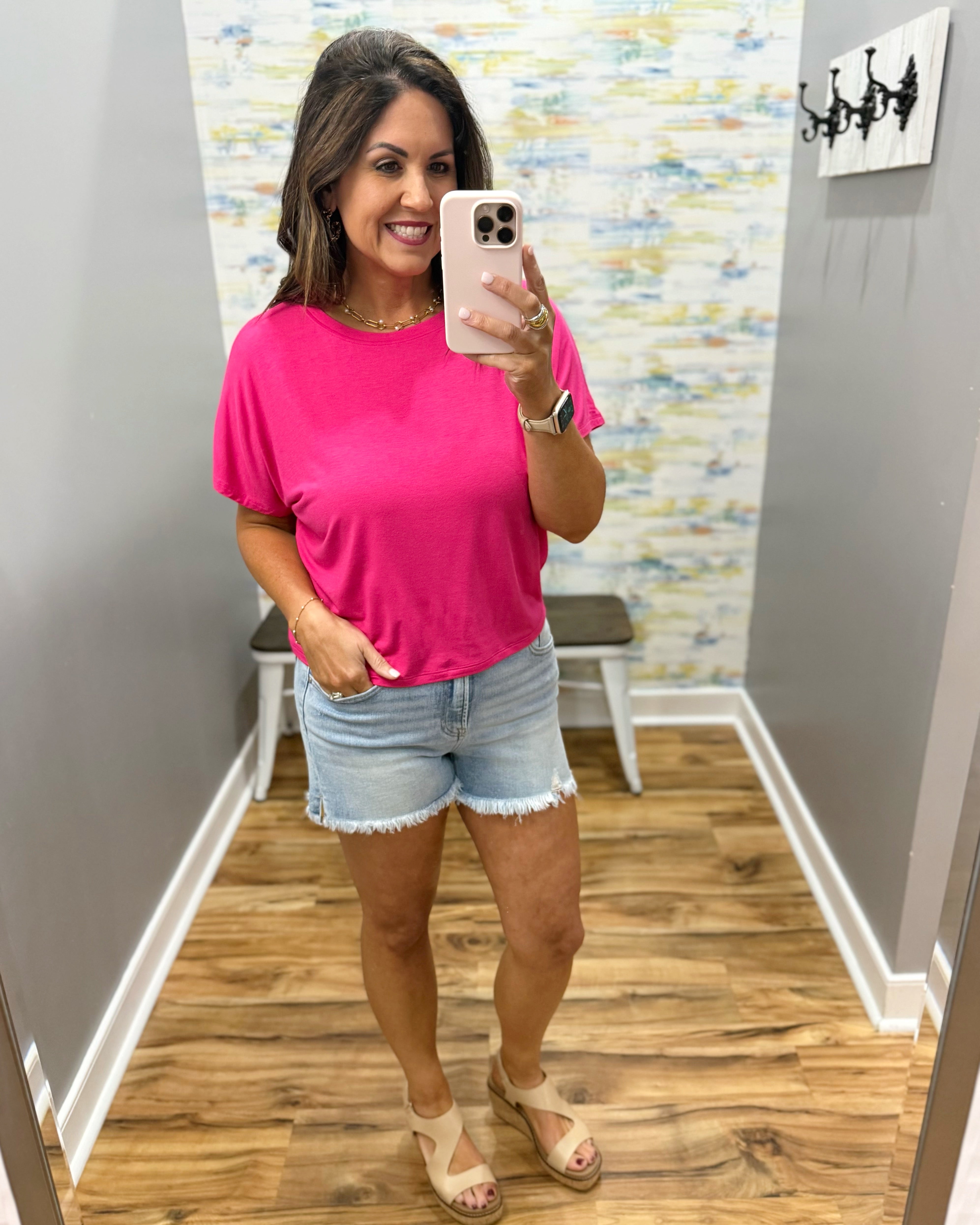 woman wearing hot pink tee with denim shorts.