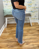 Person wearing blue jeans standing on a wooden floor with a colorful wall in the background