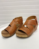 Pair of brown sandals with woven straps on a white background