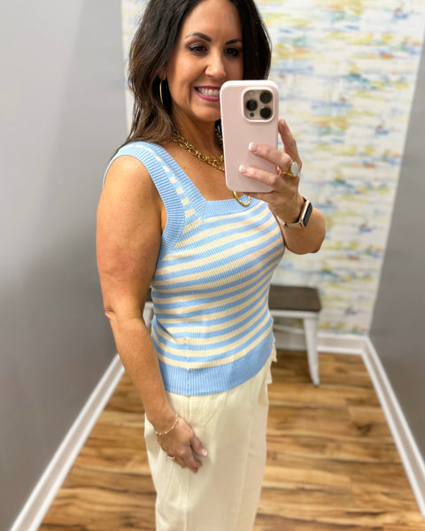 Woman wearing a blue and yellow striped sleeveless top.