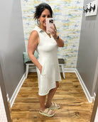 Woman taking a mirror selfie wearing a white dress in a store.
