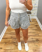 Person wearing black and white striped shorts with a plain background