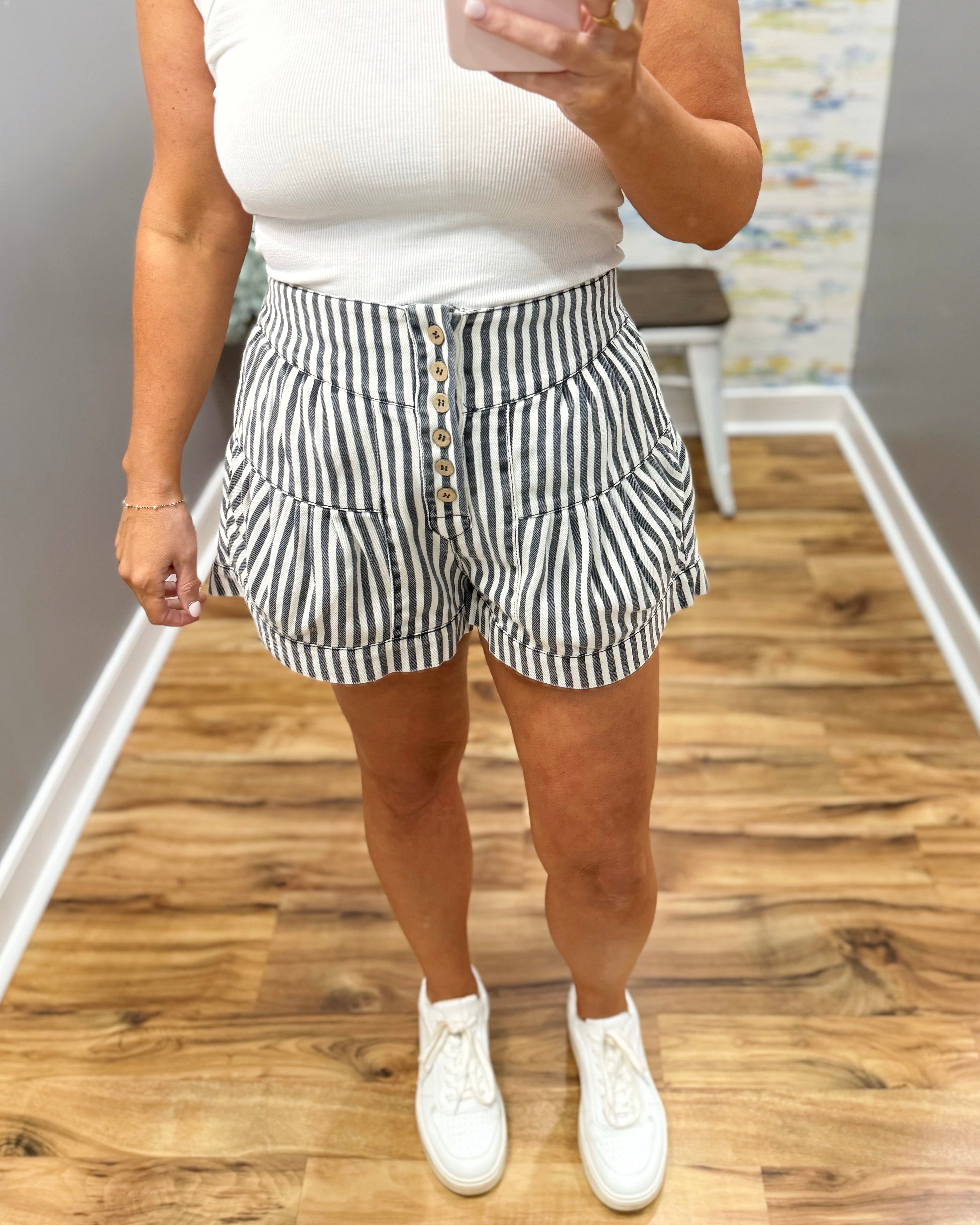 Person wearing black and white striped shorts with a plain background