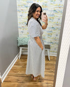 Woman wearing a striped dress in a room with a textured wall.