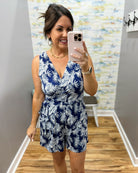 Woman taking a mirror selfie wearing a blue and white floral romper.
