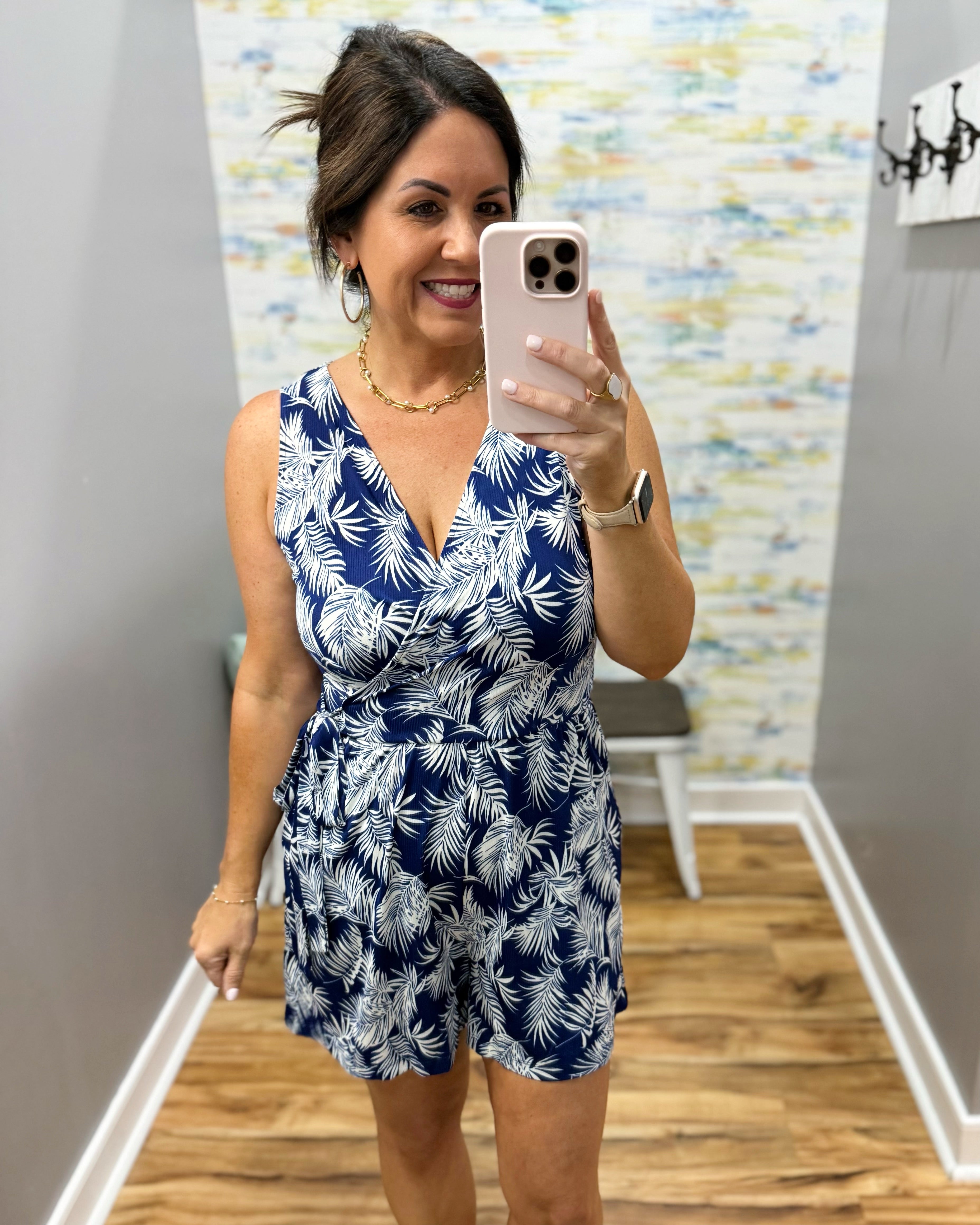 Woman taking a mirror selfie wearing a blue and white floral romper.