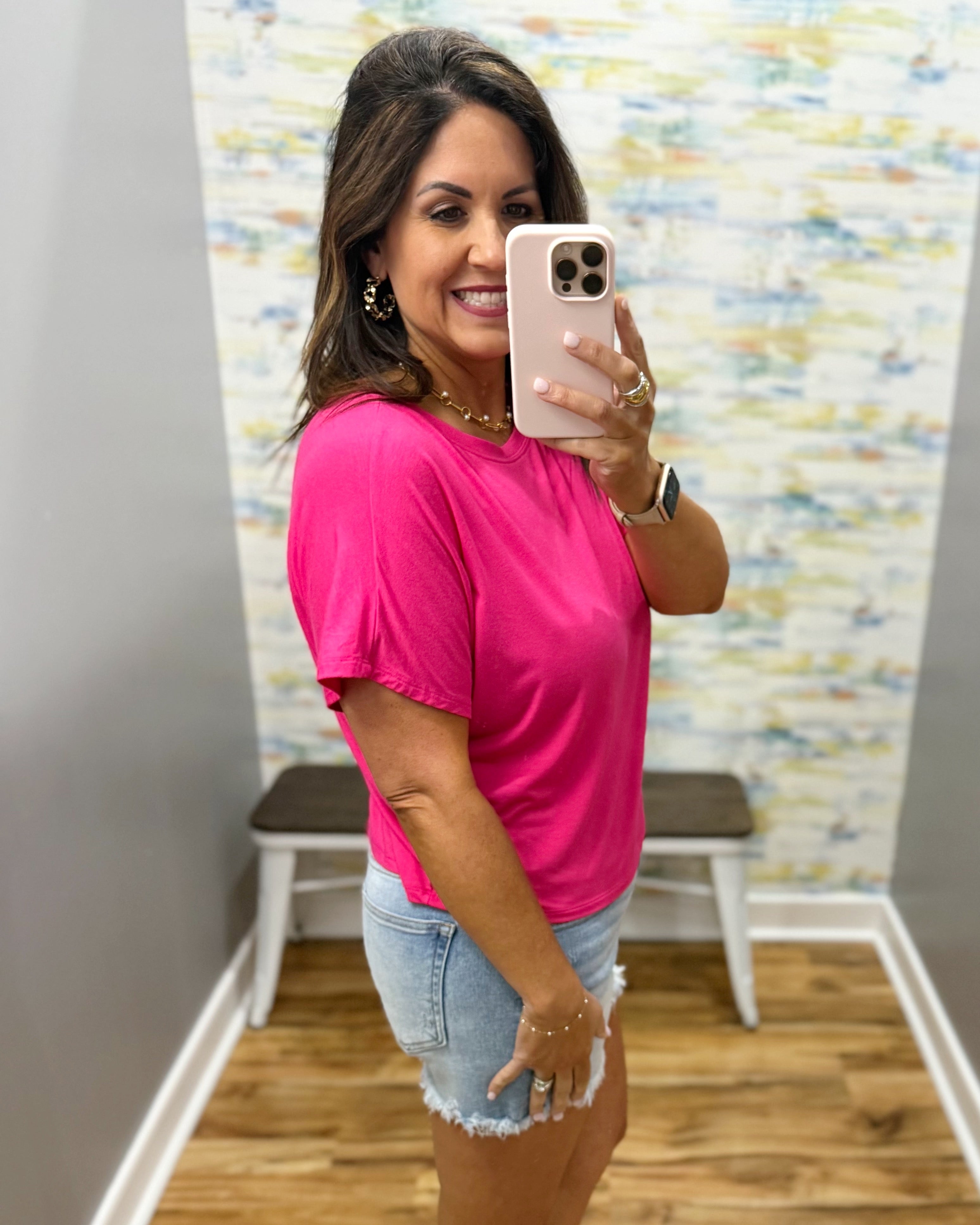 woman wearing hot pink tee with denim shorts.