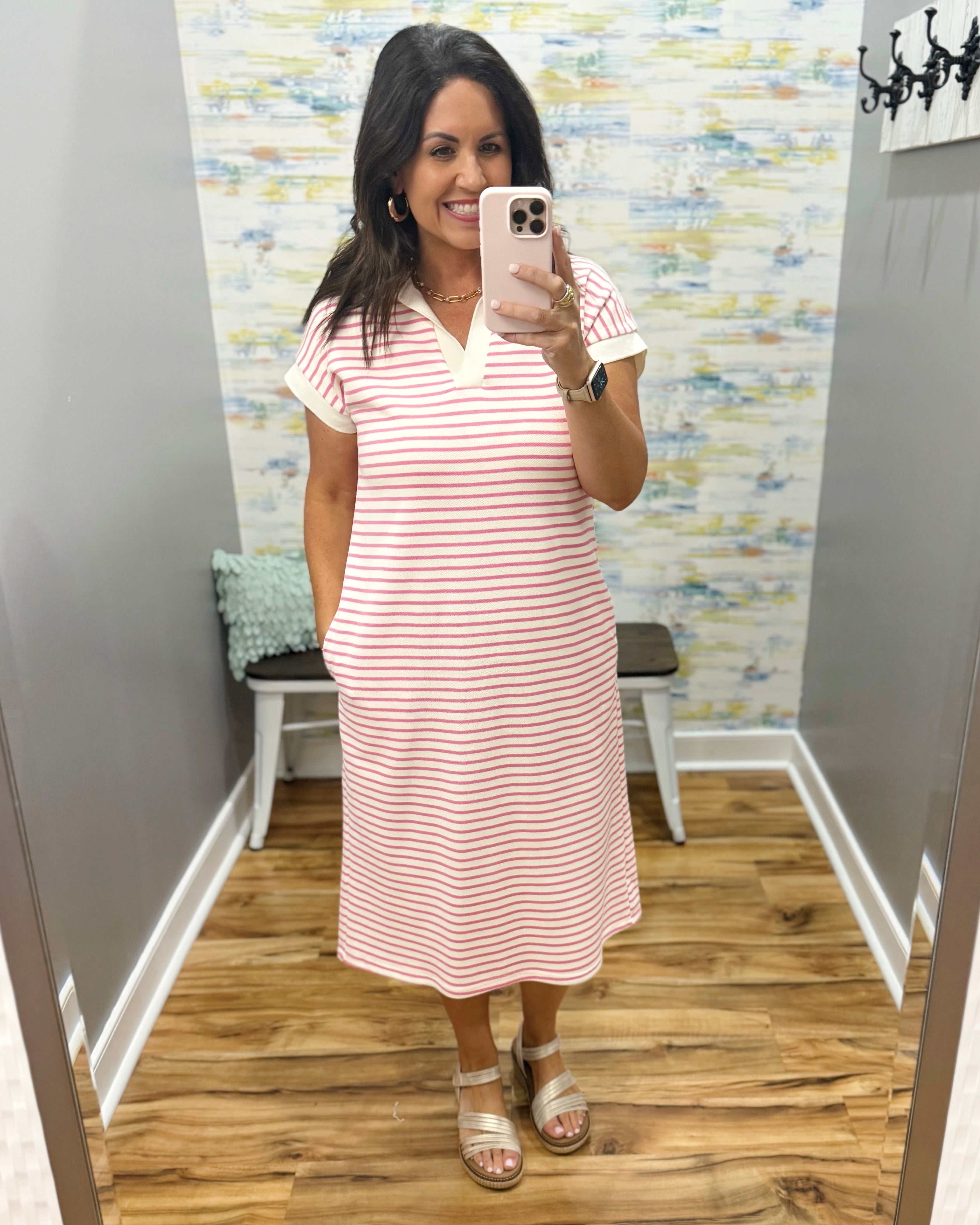 Woman taking a mirror selfie wearing a red and white striped dress in a fitting room.
