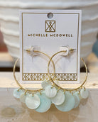 Gold hoop earrings with light green circular charms on a Michelle McDowell branded card.