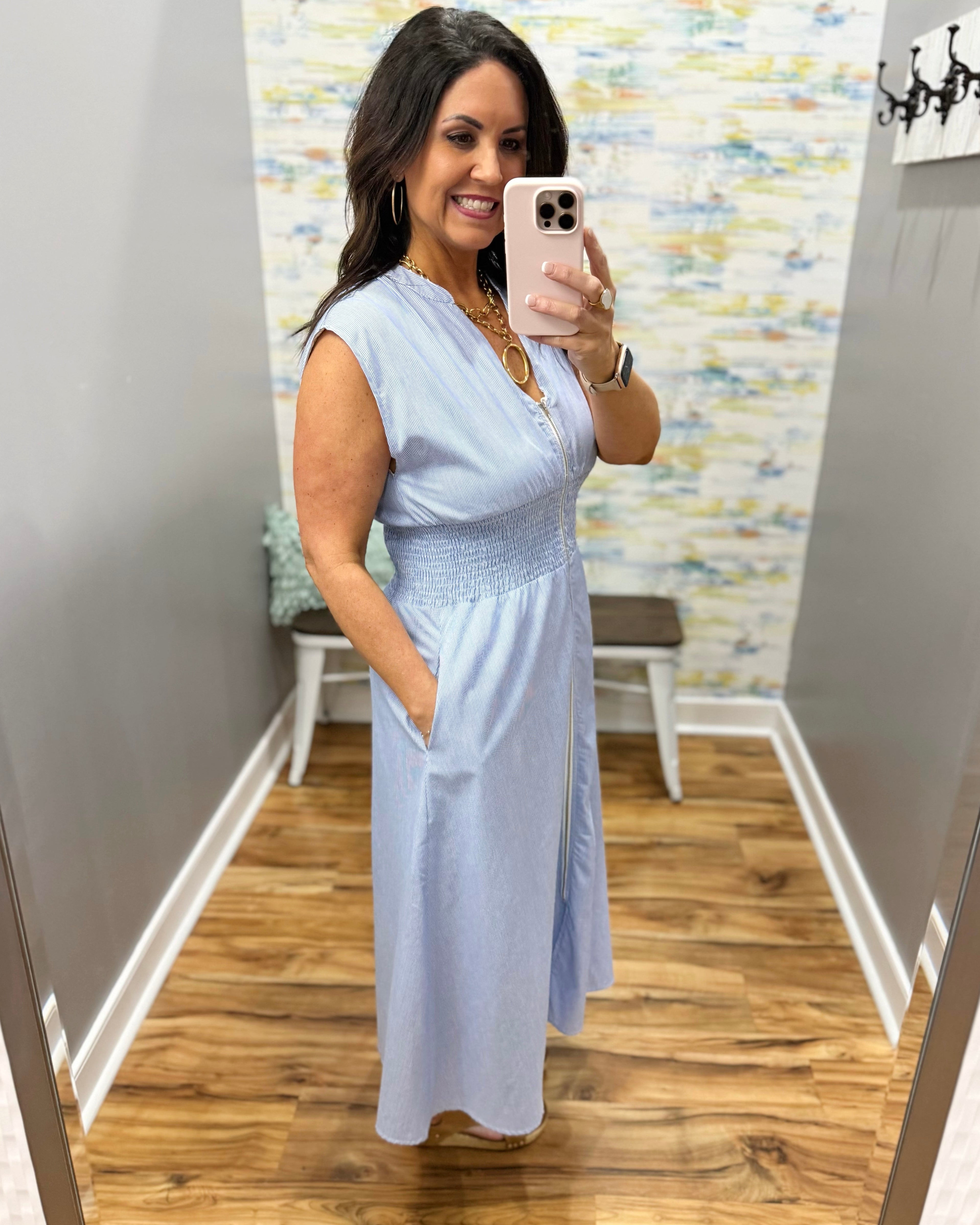 Woman wearing a light blue dress in a room with a patterned wall.