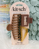 Kit Sch claw clips in a 3-piece set, packaged on a beige card. The set includes a large taupe-brown claw clip, a medium brown claw clip, and a translucent amber-yellow claw clip.