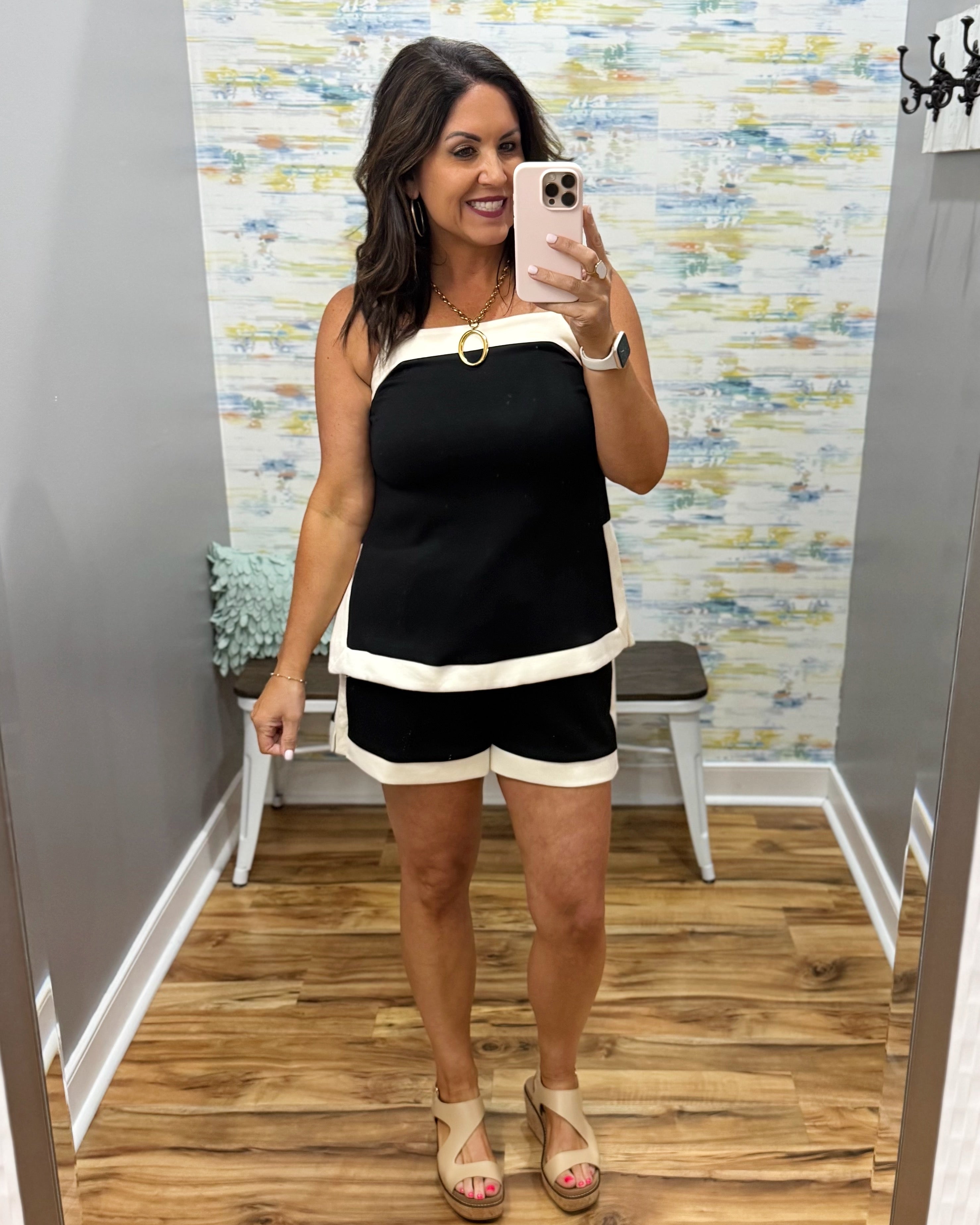 Woman taking a mirror selfie wearing a black and white outfit in a store.