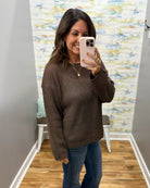 woman taking a selfie wearing a brown crochet knit sweater.