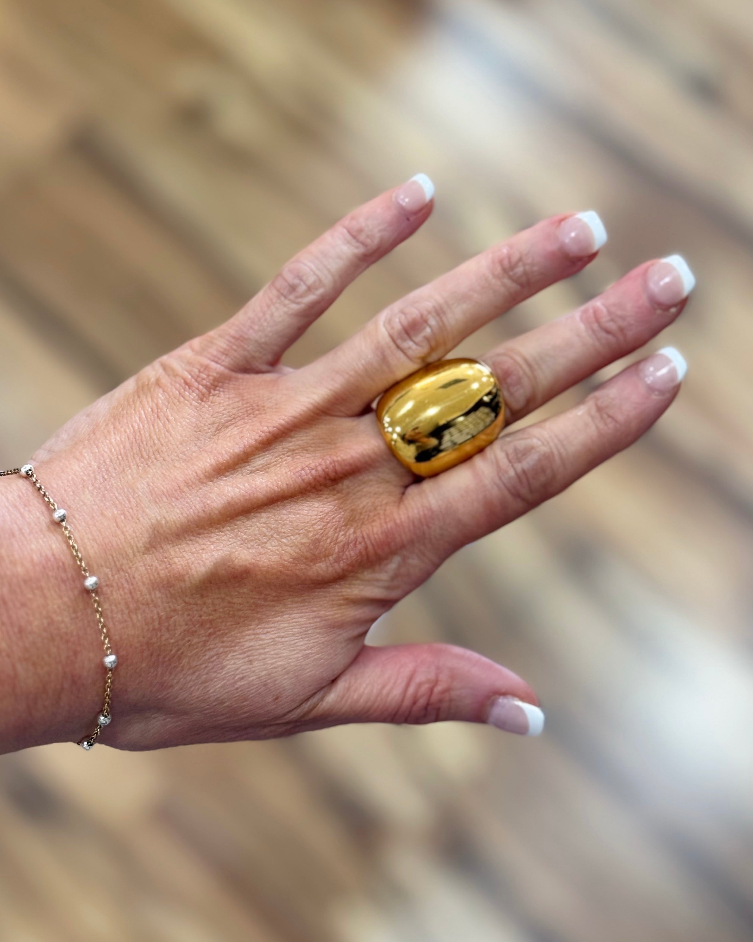 Hand wearing a gold ring with a blurred background