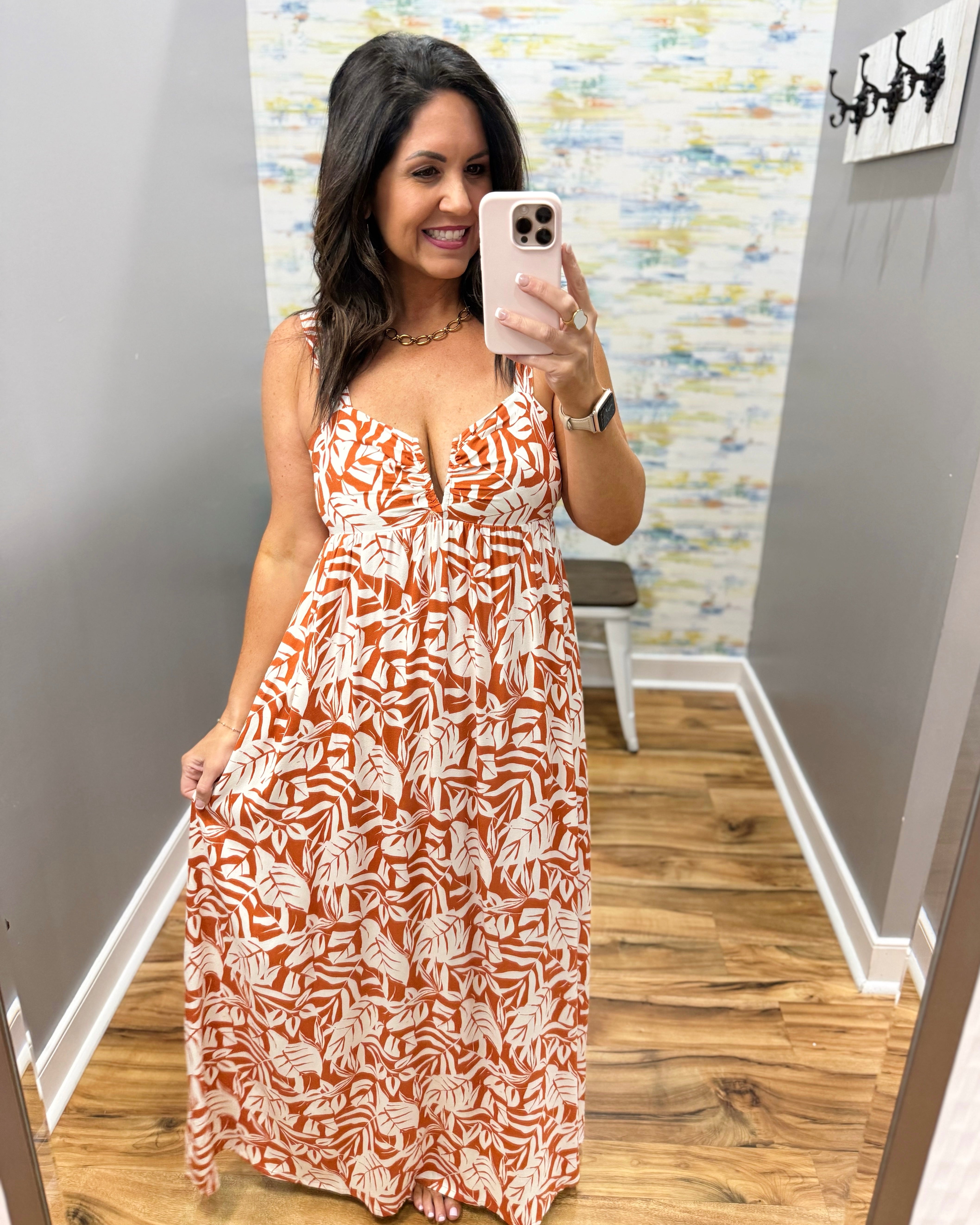 Woman taking a mirror selfie wearing a patterned dress in a room with a colorful wall.