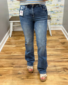 Person wearing blue jeans with a tag, standing on a wooden floor.