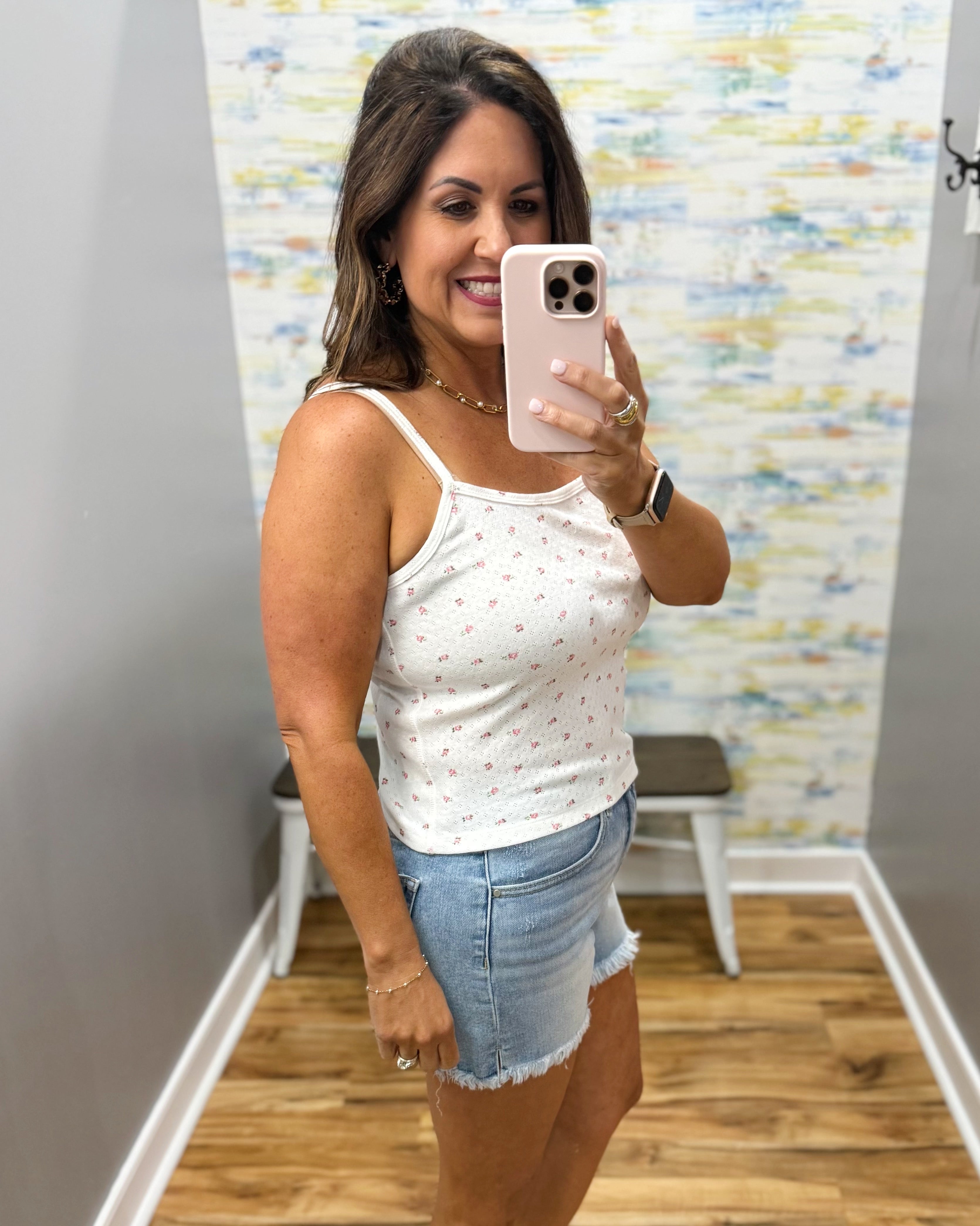woman wearing white floral cami top with denim shorts.