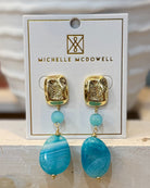 Gold and turquoise earrings on a Michelle McDowell branded card.