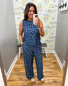 Woman taking a mirror selfie wearing a navy blue outfit with white polka dots in a room.