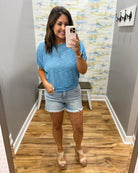 woman wearing a blue top with denim shorts.