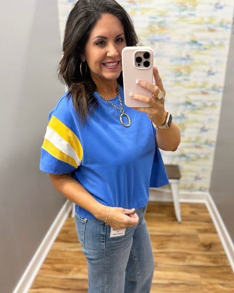woman wearing blue tee with chunky gold necklace