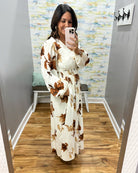 woman wearing a cream maxi dress with brown, black and taupe floral pattern. 