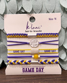 A set of five K'lan's hair tie bracelets in purple, yellow, and white, displayed on a branded card. The set includes braided and flat elastic bands with 'GAME DAY' text and a central charm that reads 'Let's Go'.