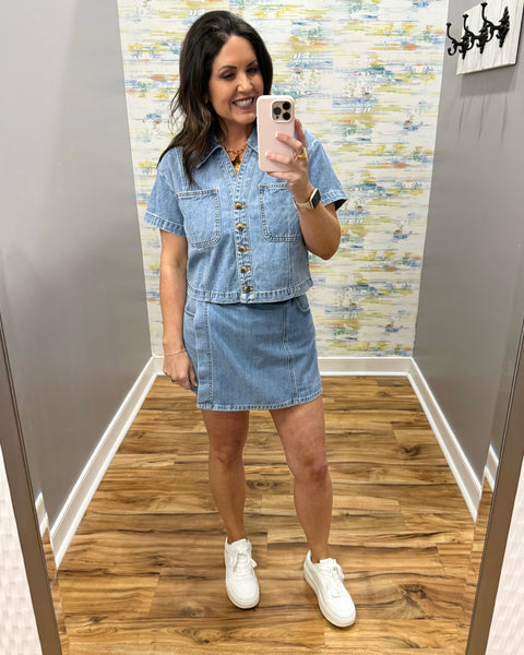 Woman wearing a denim skort and denim top with beige boots.