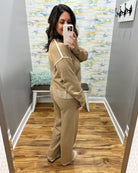 woman taking a selfie wearing a two-piece set in mocha with cream pipe stitching.  Set includes pants and long sleeve top.