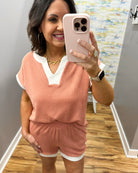 Woman taking a mirror selfie wearing a pink outfit with a white shirt underneath.