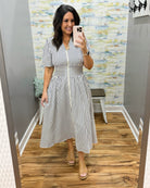 Woman wearing a striped dress in a room with a patterned wall.