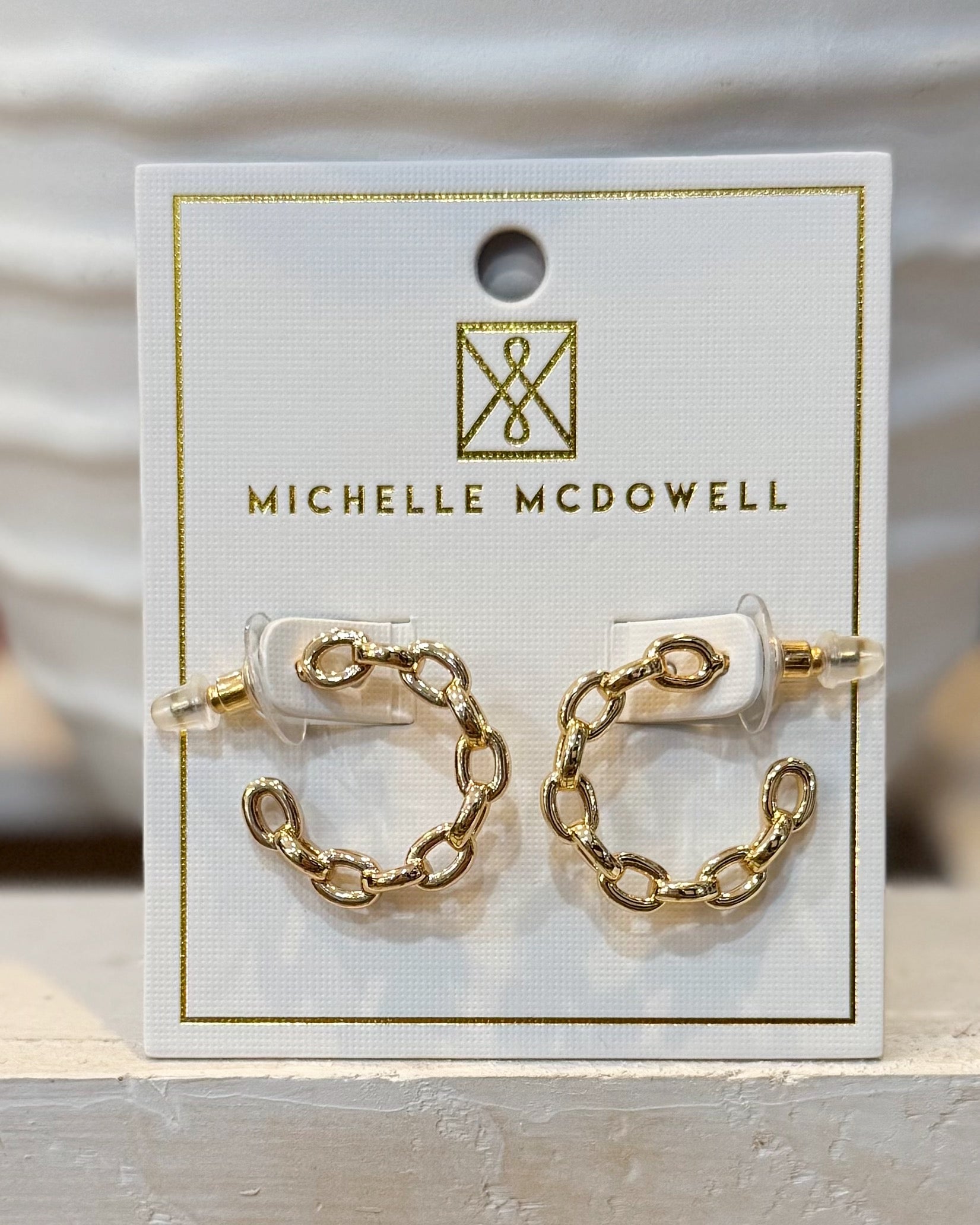 Gold chain earrings on a Michelle McDowell branded card.