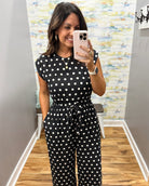 woman taking a selfie wearing a black and white polka dot jumpsuit.