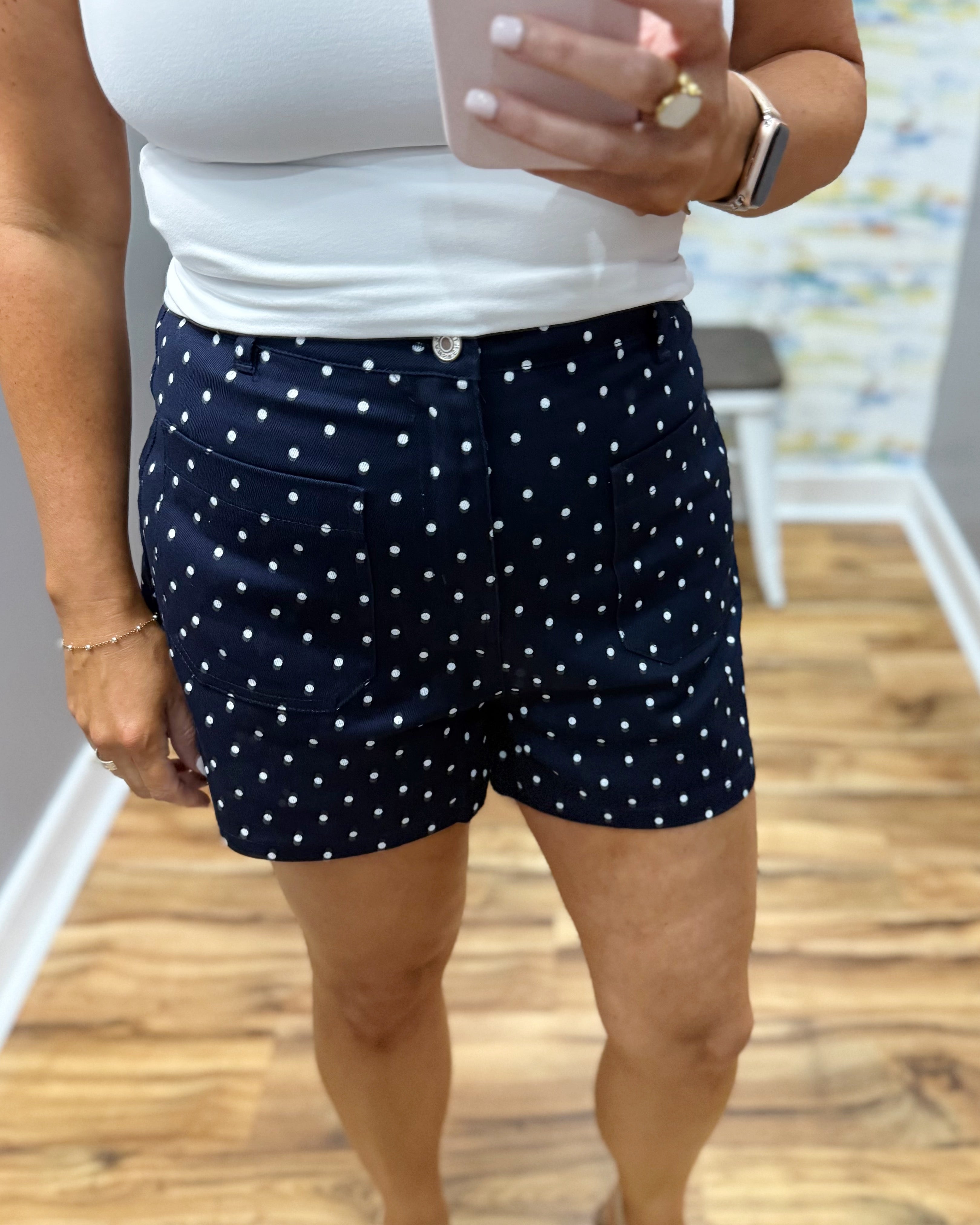 Person wearing navy shorts with white polka dots indoors.
