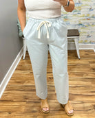Person wearing light denim pants with a white top in a room with wooden flooring and a colorful wall.