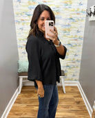 woman wearing a black 3/4 sleeve flowy top.