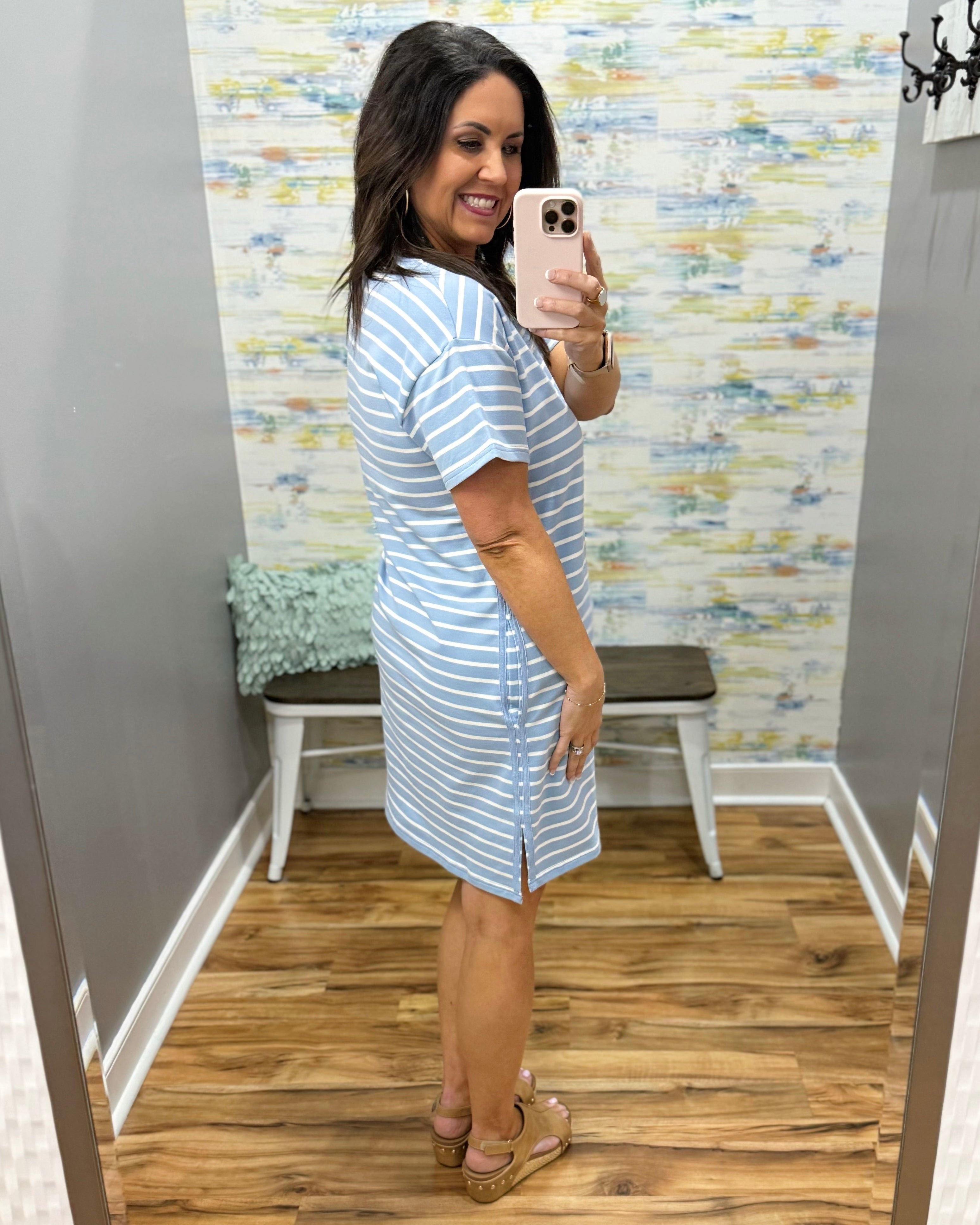 Woman wearing a blue and white striped dress in a fitting room.
