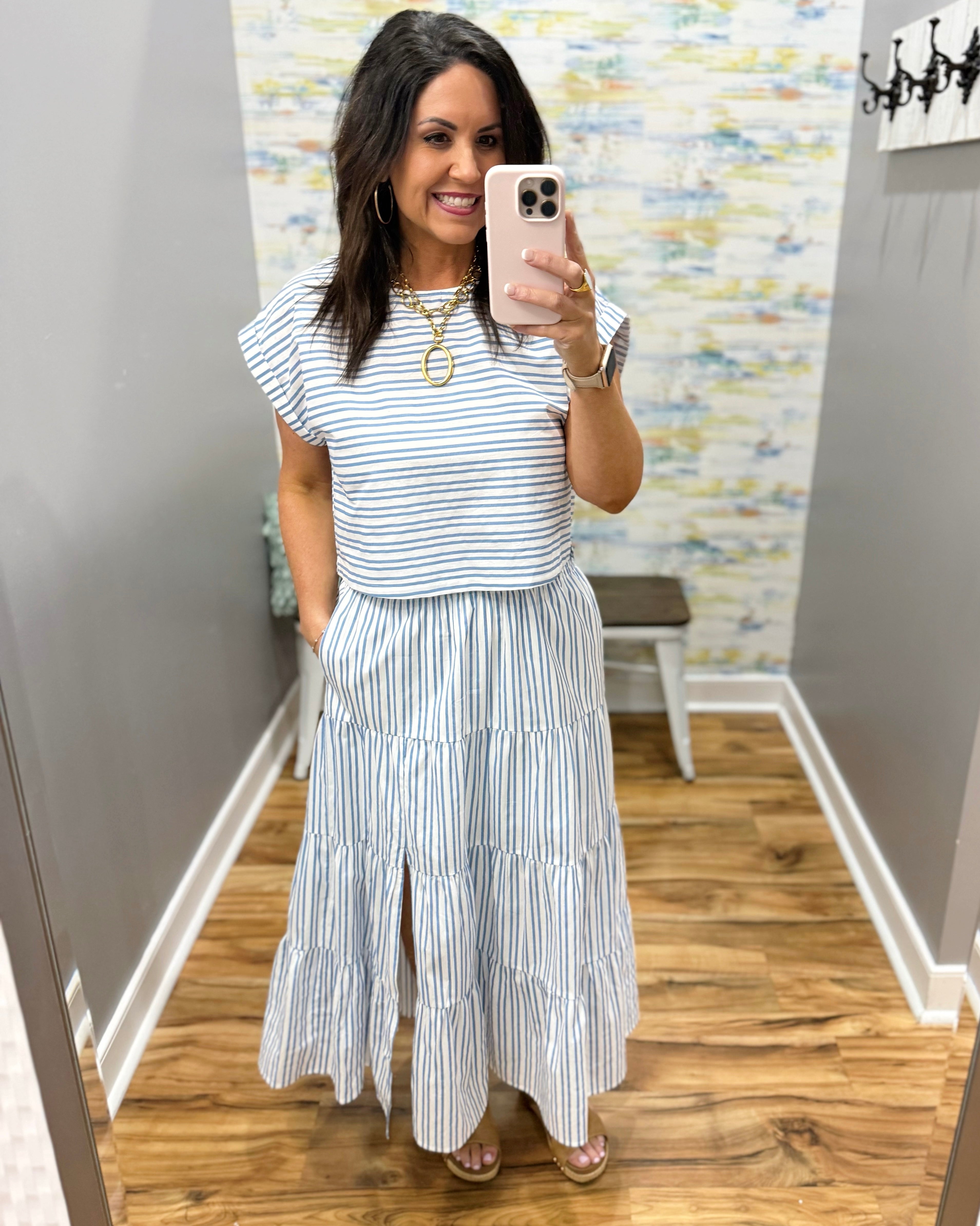 Woman wearing a striped outfit in a room with a patterned wall.