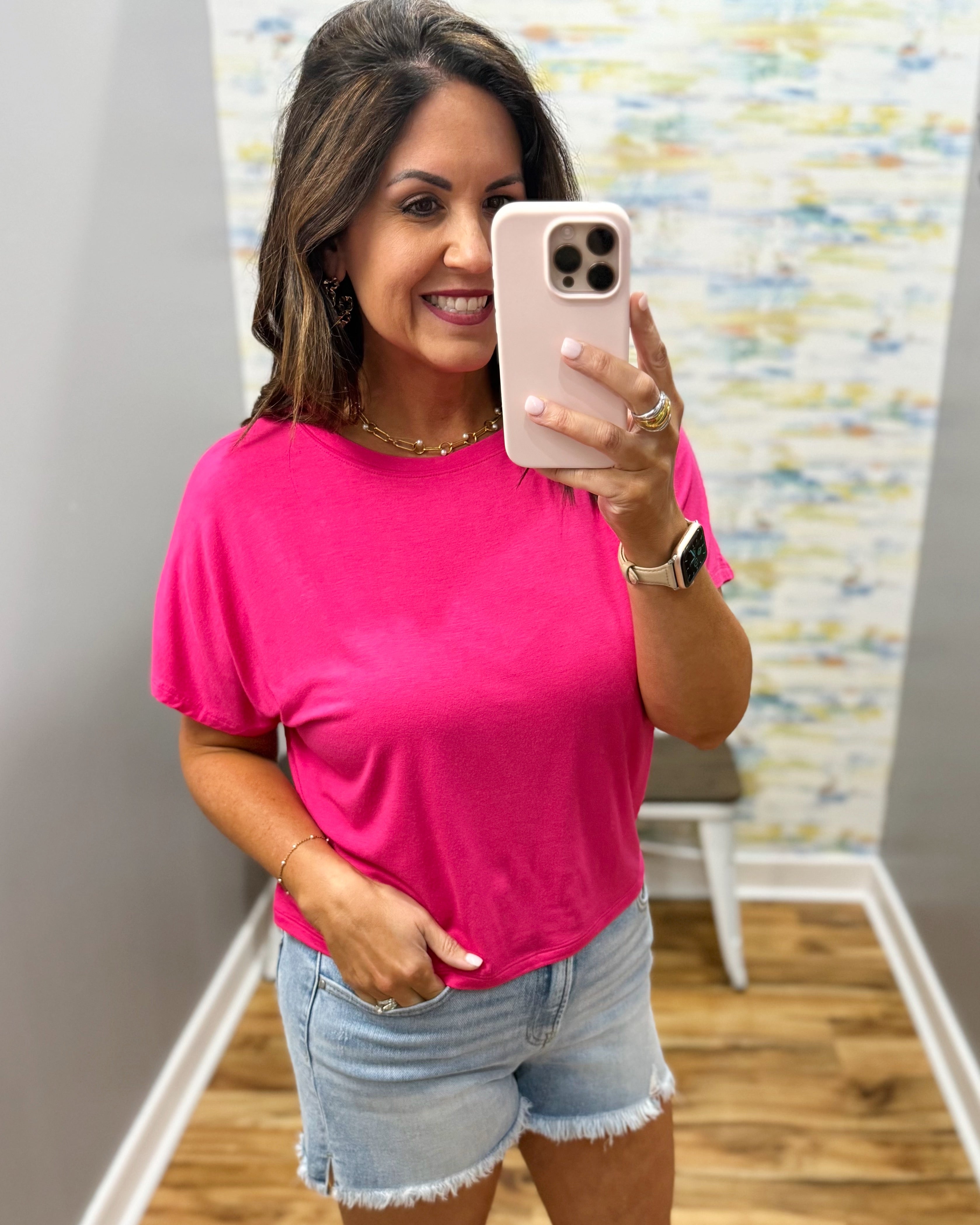 woman wearing hot pink tee with denim shorts.