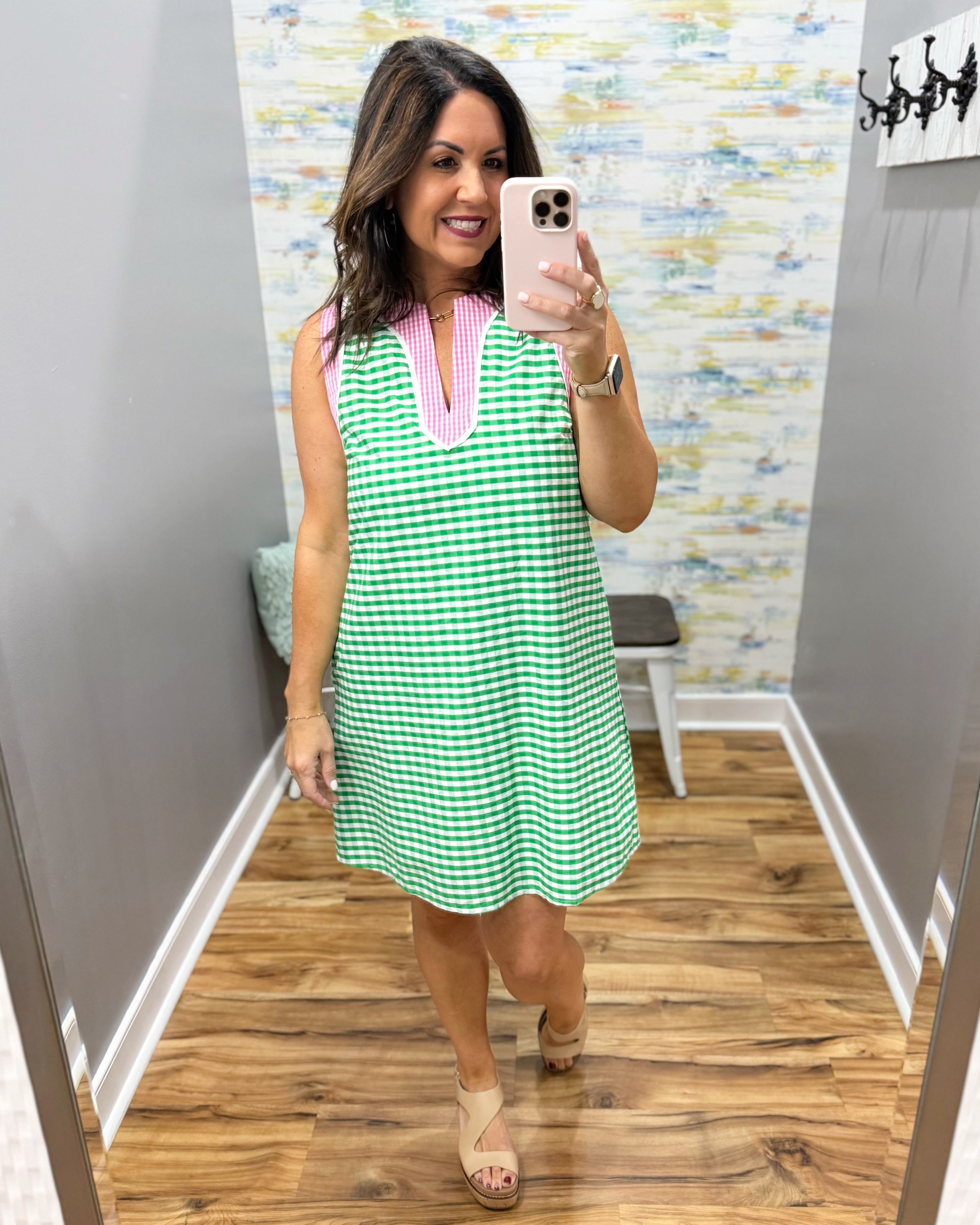 Woman taking a mirror selfie wearing a green and white checkered dress with pink accents.
