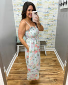Woman taking a mirror selfie wearing a floral dress in a room with a colorful wall.