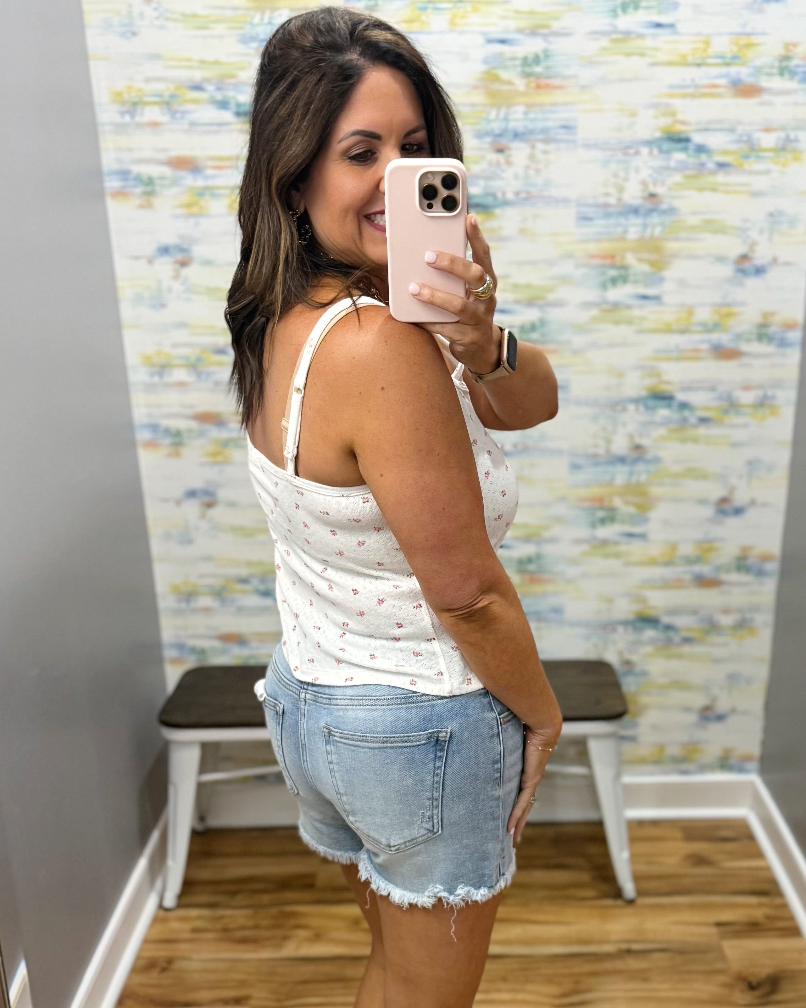 woman wearing white floral cami top with denim shorts.