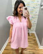 Woman taking a mirror selfie wearing a pink and white striped dress.