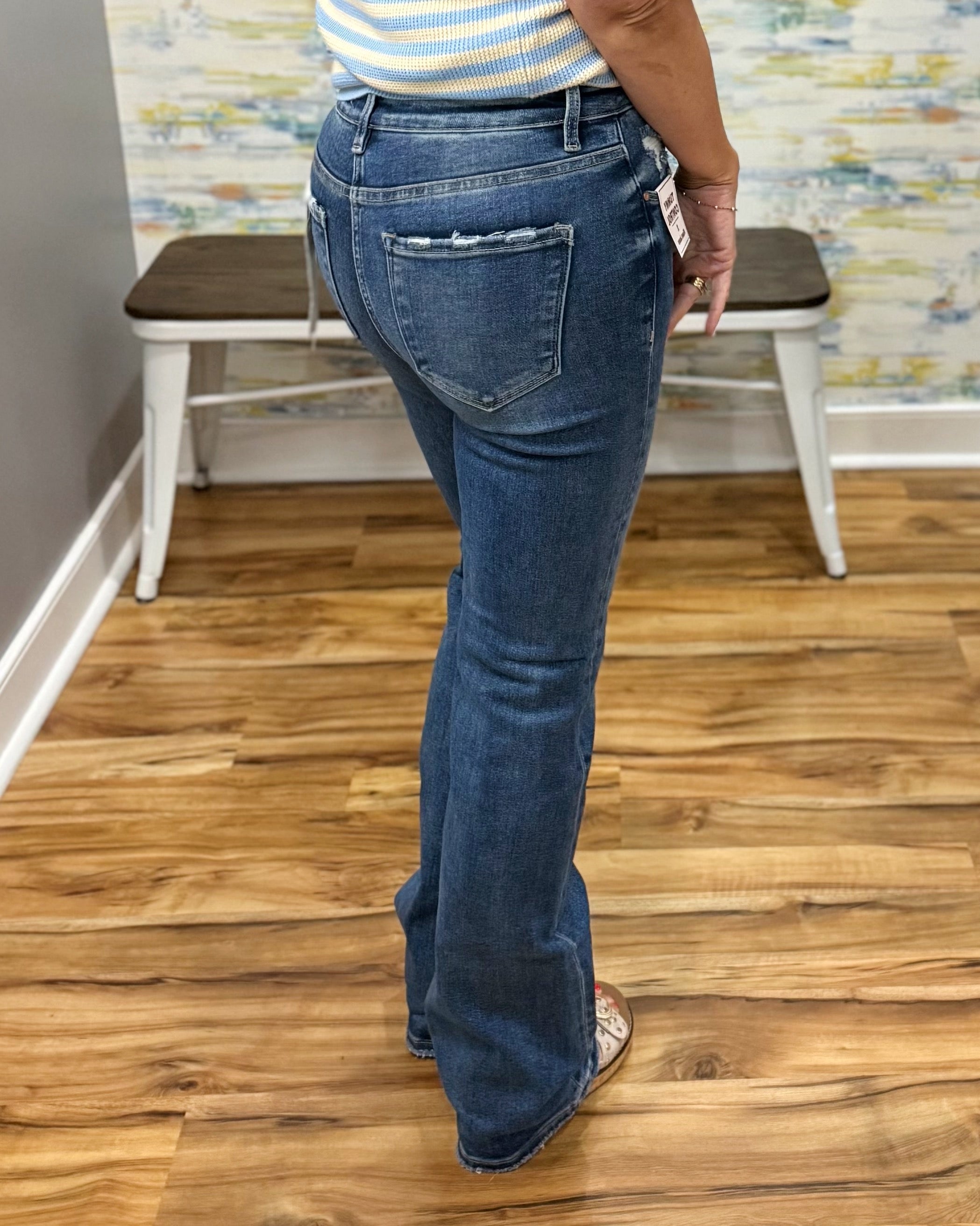 Person wearing blue jeans standing on a wooden floor with a colorful wall in the background